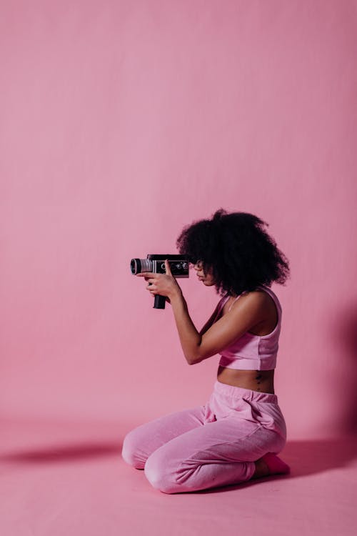 Woman in Pink Crop Top and Jogging Pants Using a Camcorder