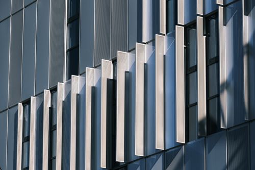 Free Close-up of a contemporary building's geometric facade with glass and metal panels. Stock Photo