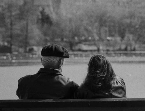 Free Grayscale Photo of a Romantic Couple Sitting on the Bench Stock Photo