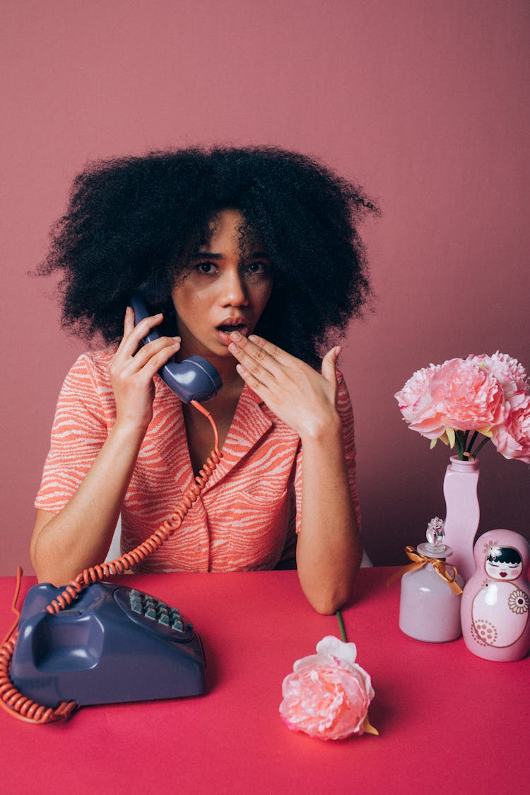 Woman Looking Surprised While Using An Old Telephone