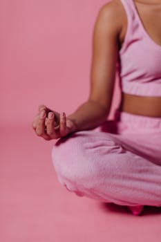 A serene woman practicing yoga meditation in pink attire, fostering tranquility and wellness.