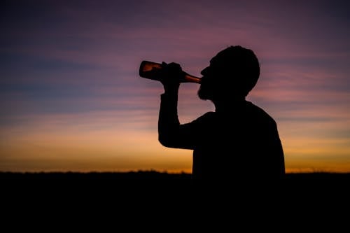 Free Silhouette of Man Drinking from Bottle during Sunset Stock Photo