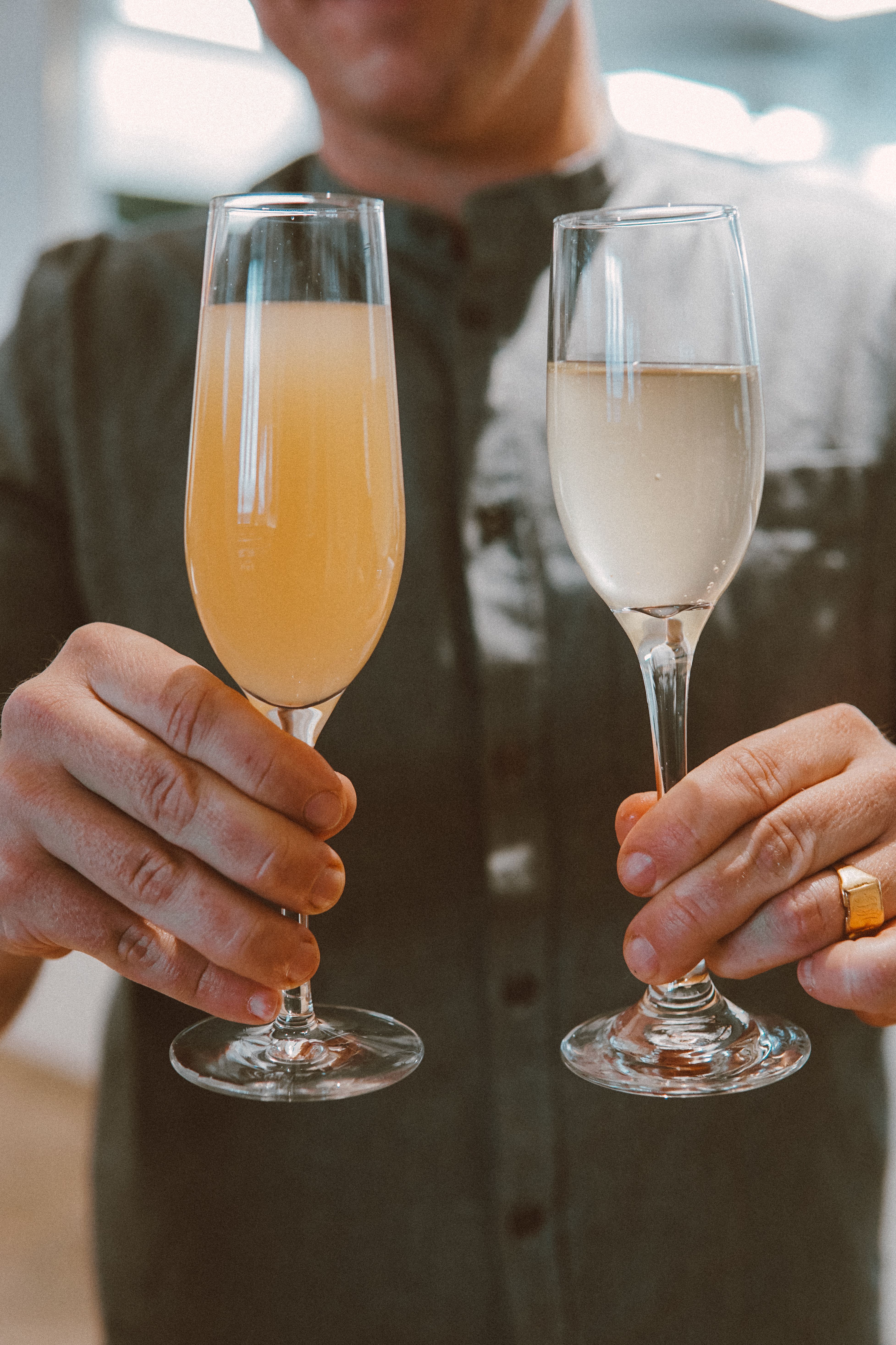 Close-up view of a man holding champagne and cocktail glasses during a festive celebration.