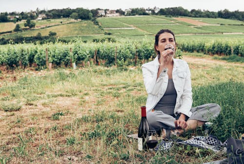 Free Woman in White Long Sleeve Shirt Sitting on Green Grass Field Stock Photo