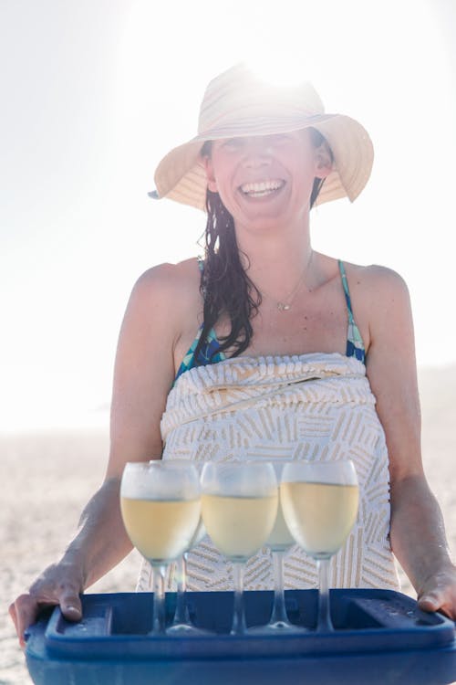 A Woman Wearing a Sun Hat Holding a Tray of Glasses with Champagne 