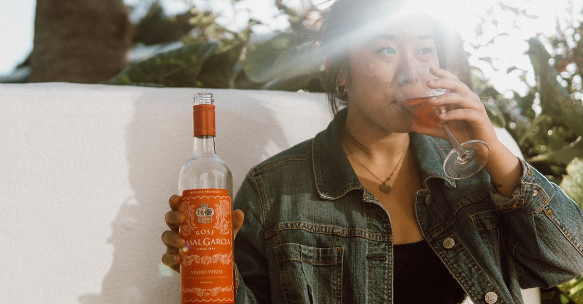 A woman savoring a glass of rosé wine in sunny outdoor setting, Portugal.