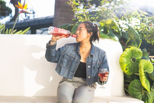 Free Woman relaxing outdoors in Portugal, enjoying wine on a sunny day, surrounded by lush greenery. Stock Photo