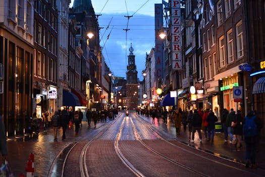 Dynamic evening street scene in Amsterdam featuring bustling crowds and illuminated shops.
