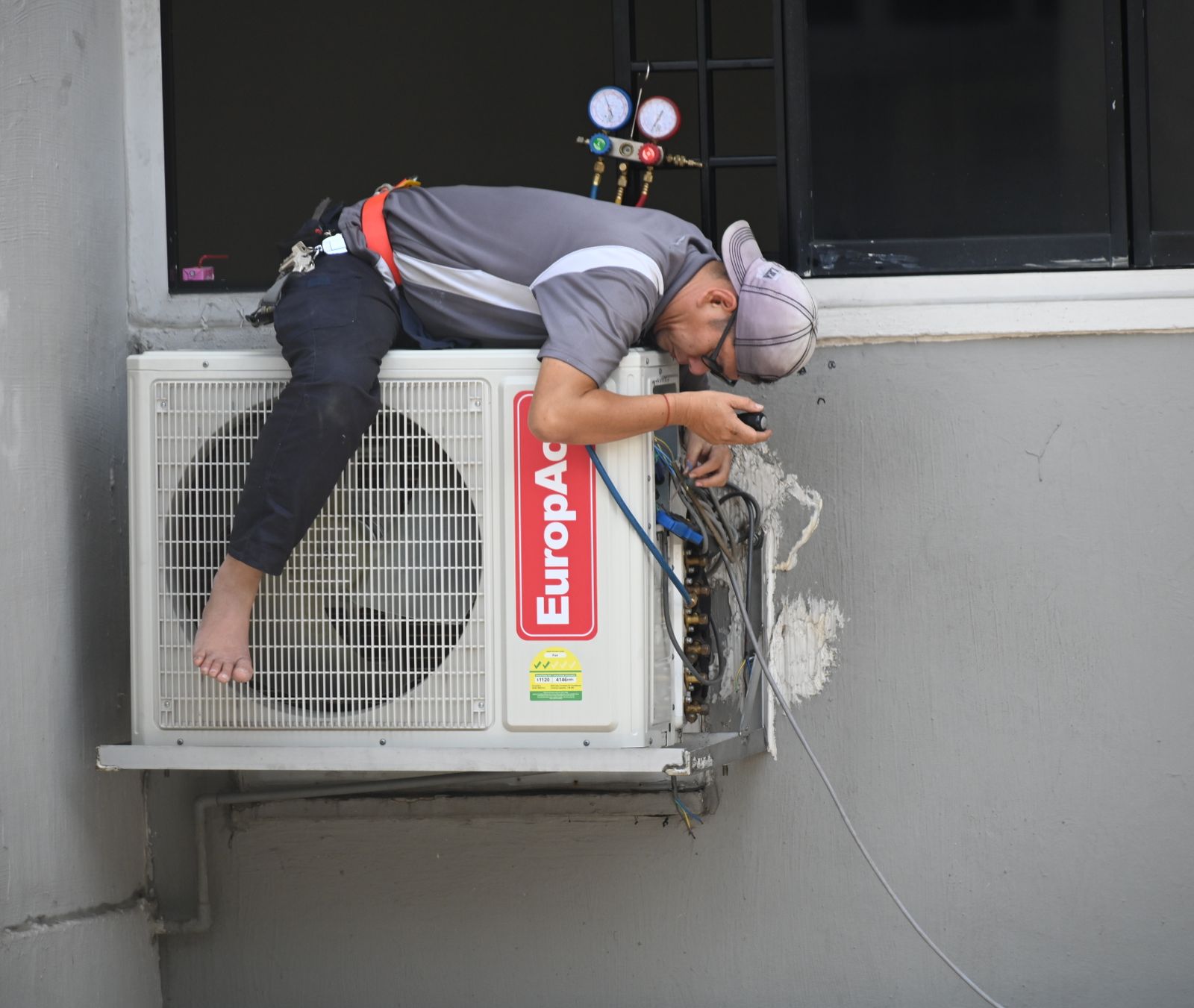 AL LIYARA technician servicing a commercial outdoor air conditioning unit