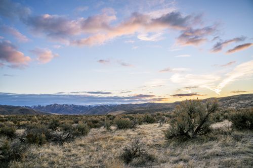 Free Peaceful landscape view of mountains and meadow at twilight with colorful sky. Stock Photo