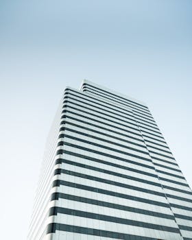 Low angle view of a sleek, striped high-rise building against a clear blue sky.