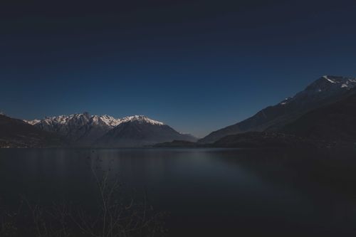 Free Beautiful night landscape of snow-capped mountains reflecting on a calm lake under a clear, starry sky. Stock Photo