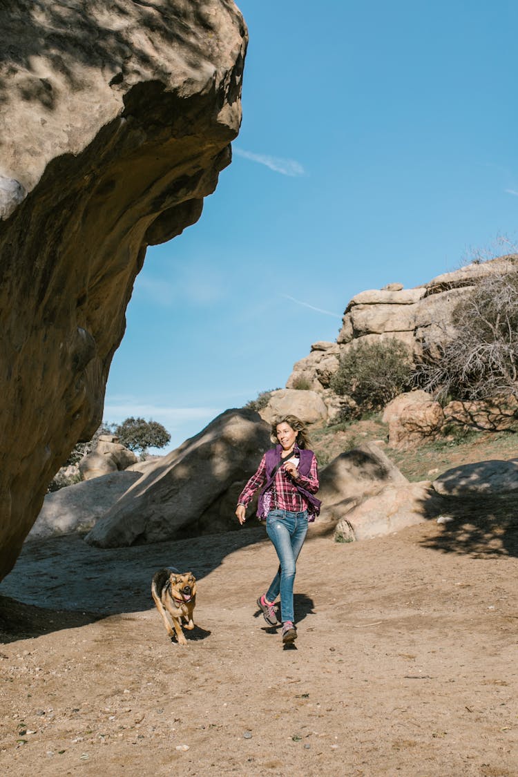 Woman In Purple And White Plaid Shirt Running With Her Brown Dog