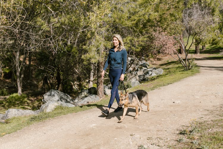 A Woman Walking Her Dog In The Park