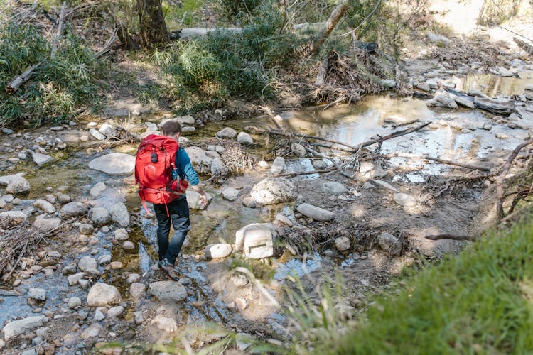 Man With Backpack Near Stream In Forest