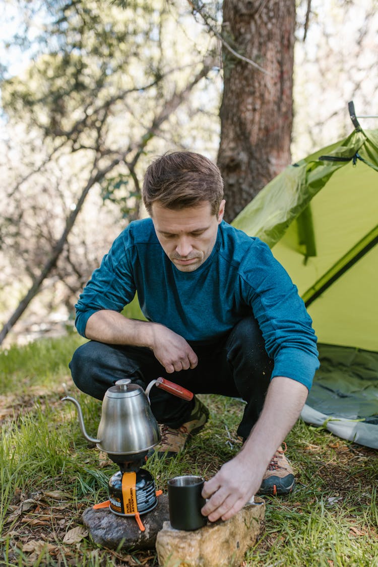 A Man Boiling Water With A Kettle