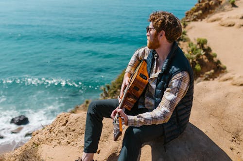 Photo of a Man with Red Hair Playing the Guitar