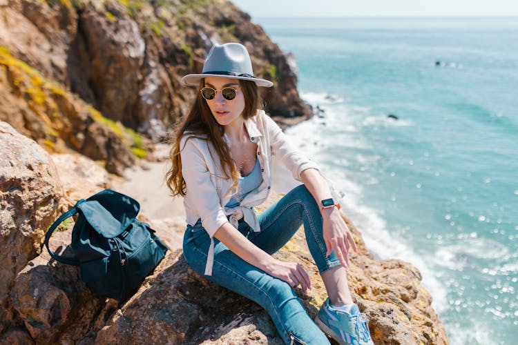 Stylish Woman Sitting On A Rock