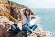 年轻女子在岩石海滩享受阳光明媚的一天，拥抱户外冒险精神