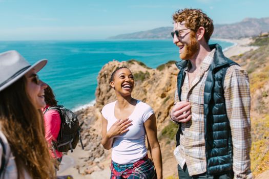 Joyful friends exploring a picturesque coastal trail under the sunny sky.