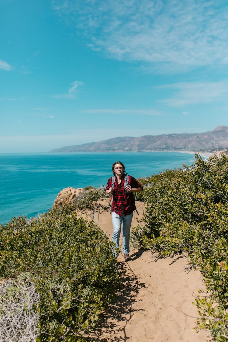 A Man In A Plaid Shirt And Denim Pants Hiking