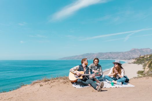 3 Women Sitting on White Sand Near Body of Water