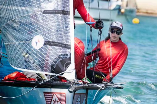 Free A woman in red sailing gear steering a sailboat on a sunny day at sea. Vibrant outdoor scene. Stock Photo