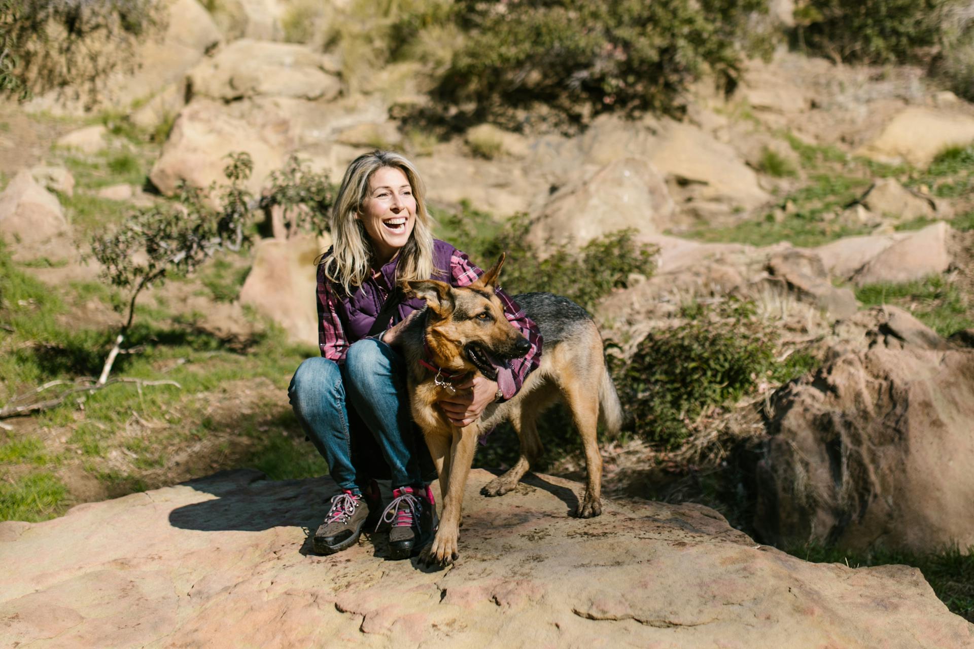 Kvinna i blå jeans sitter bredvid en schäferhund