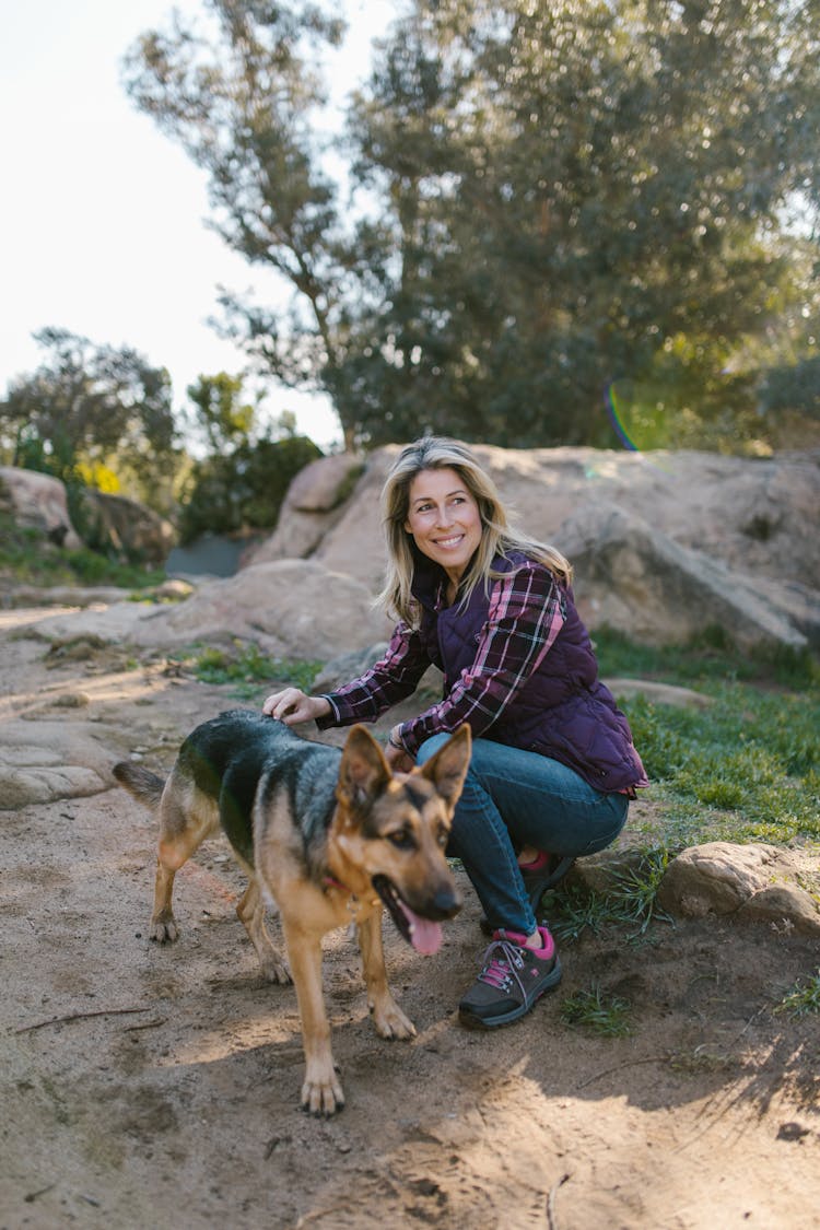 Woman Squatting Near A Dog