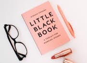 白色背景上，一本书、一副眼镜、一支钢笔和一支口红平放