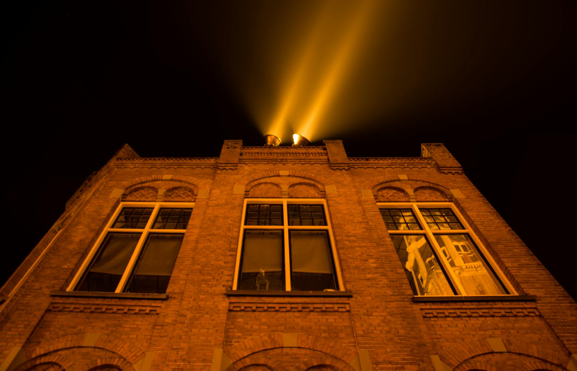 A night shot of a historical brick building with light beams in Groningen, Netherlands.