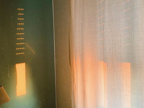 Soft golden light filtering through curtains creates a cozy ambiance in an indoor setting.
