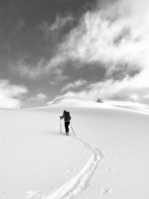 A solitary hiker trekking through a vast snow-covered landscape in winter.