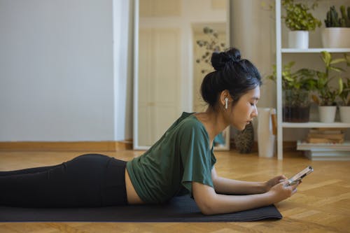 Woman Lying on Yoga Mat Using Smartphone