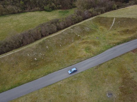 Drone shot of a car traveling on a rural road in Sharpenhoe, England.