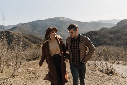 Two mature adults walking hand in hand outdoors on a scenic path