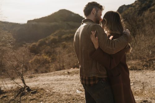 Free A couple sharing a romantic embrace amidst picturesque mountain scenery during the day. Stock Photo