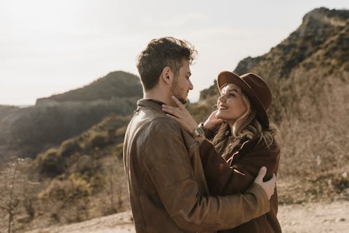 A Man in Brown Jacket Embracing a Woman in Brown Coat