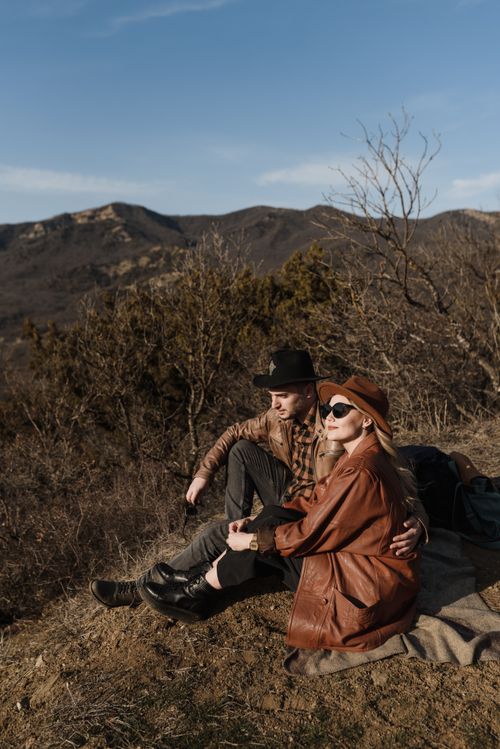 Free Couple sitting on a hill enjoying a mountain sunset. Stock Photo