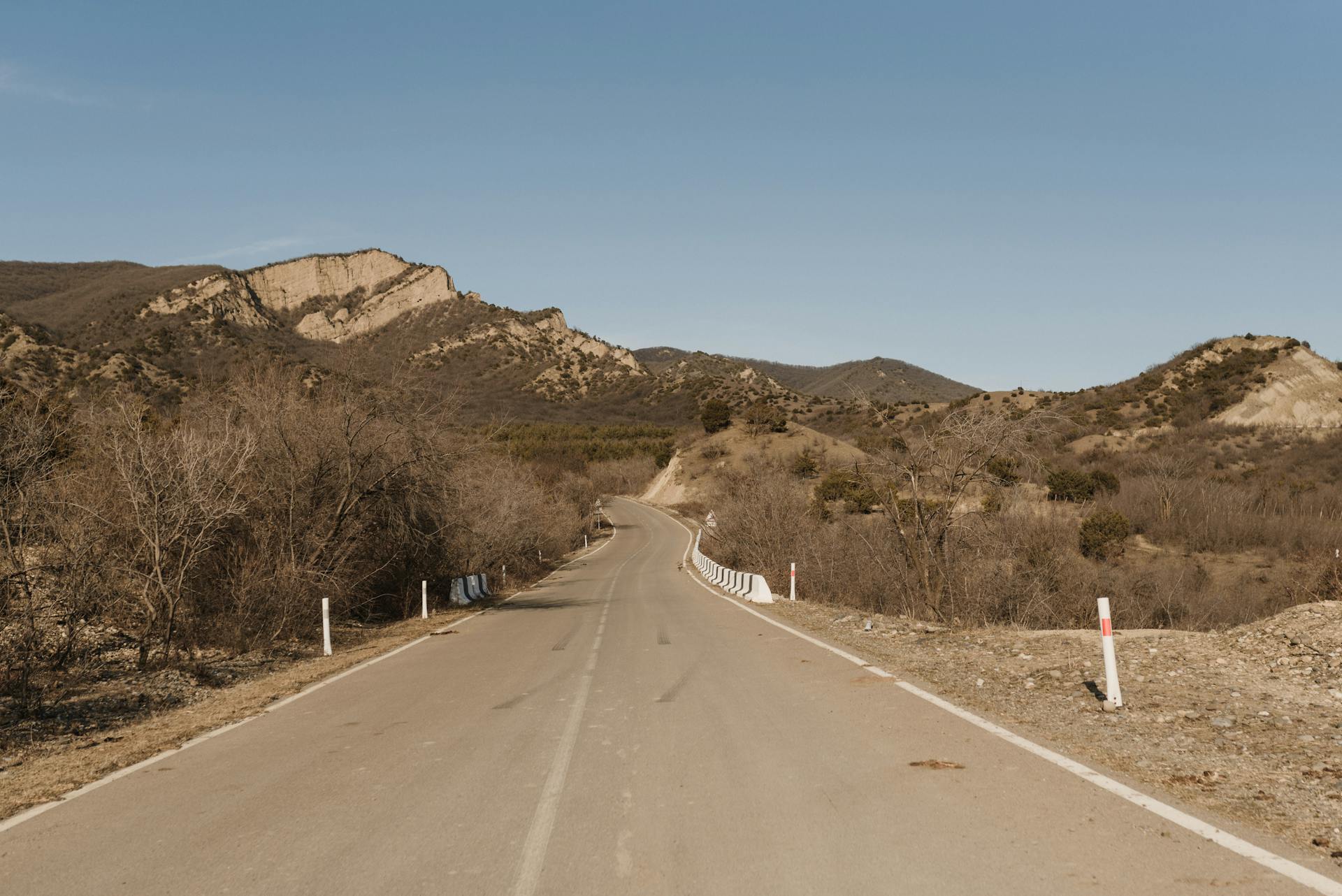 Concrete Road near Mountains under the Blue Sky