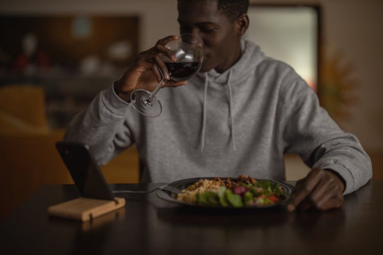 Man In Gray Dress Hooded Jacket Drinking Wine