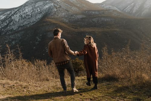 Free A couple holding hands and embracing love while exploring a mountainous landscape. Stock Photo