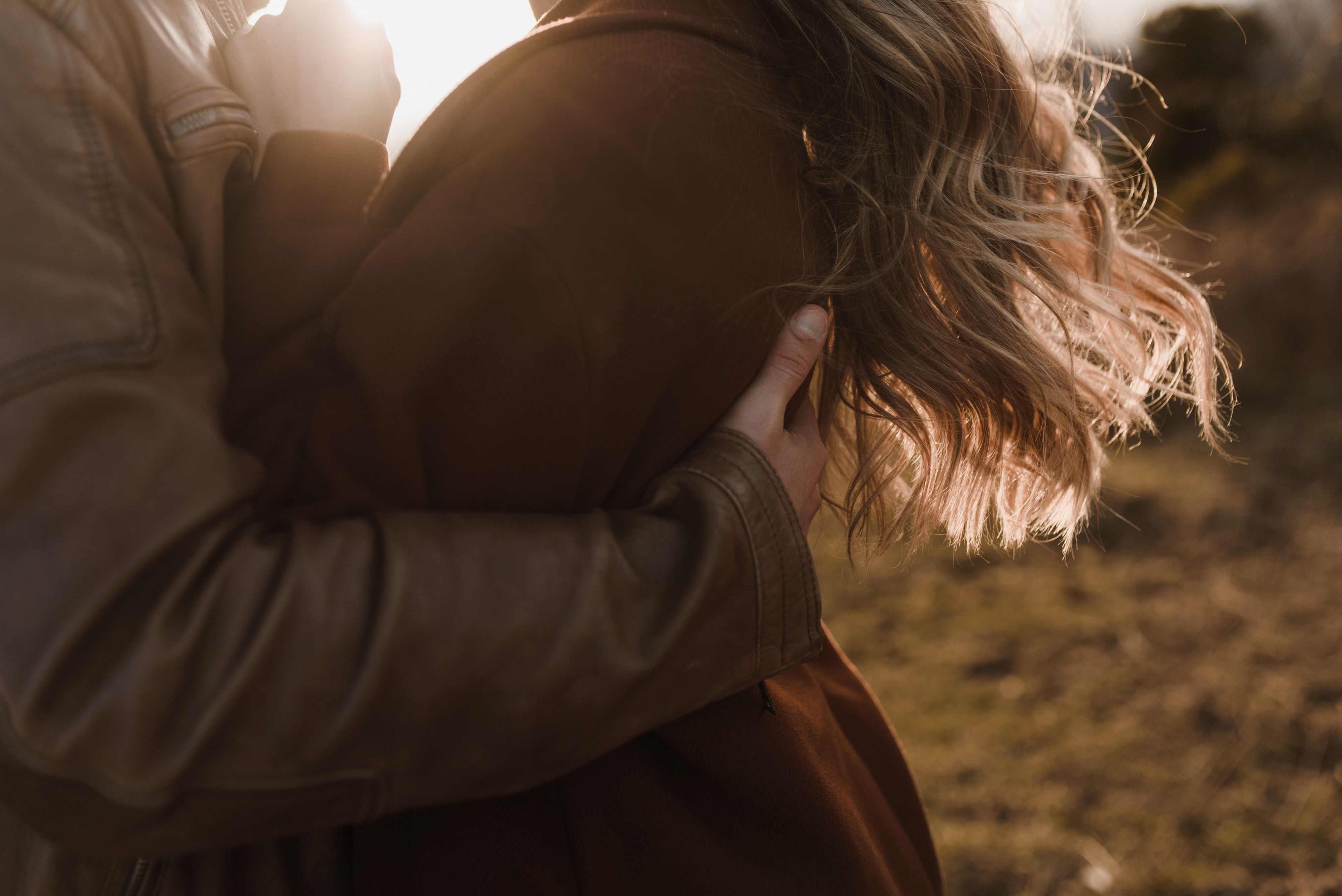 A couple embraces warmly, bathed in the gentle glow of sunset.