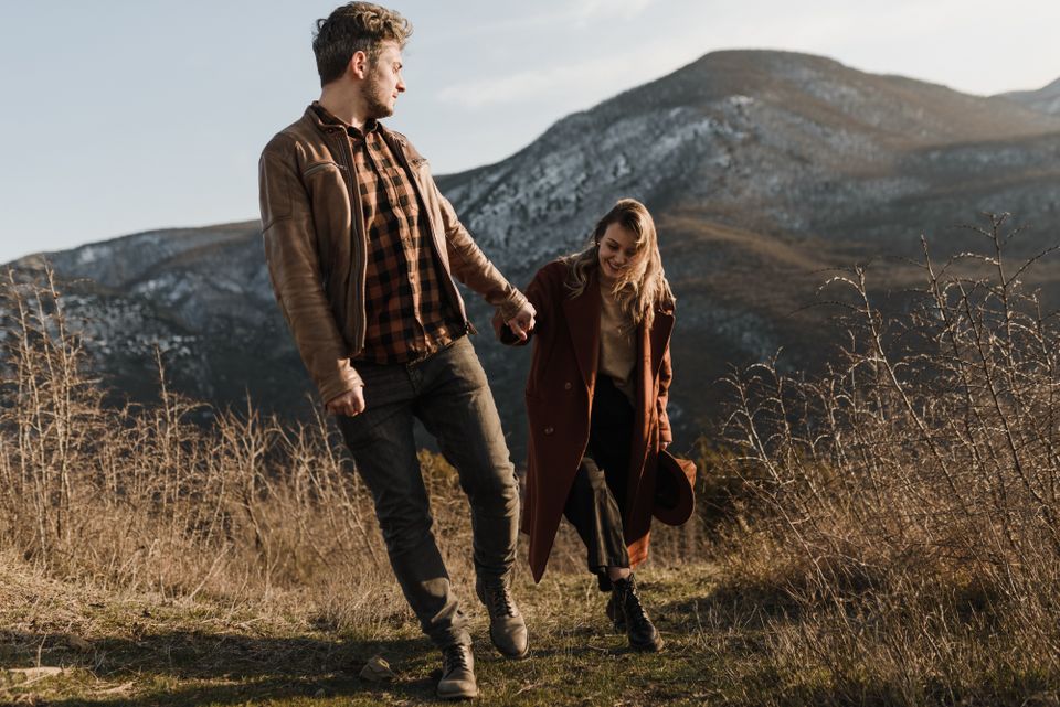 A couple holding hands while walking in the mountains