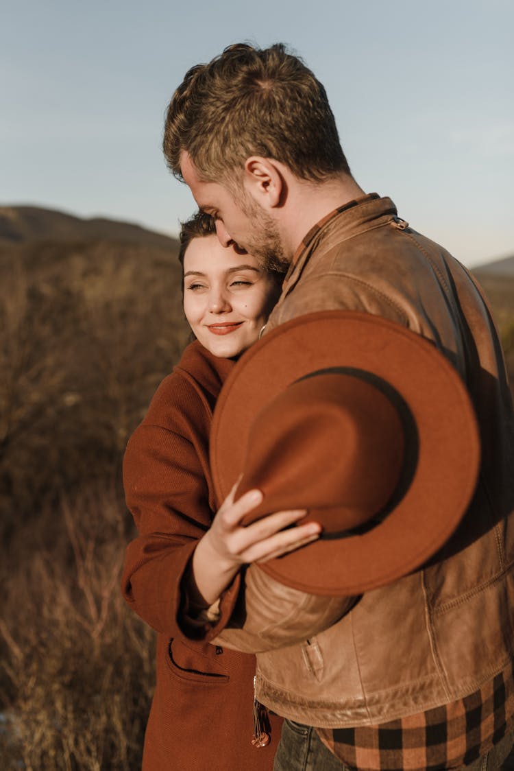 Man Hugging Woman Holding A Hat