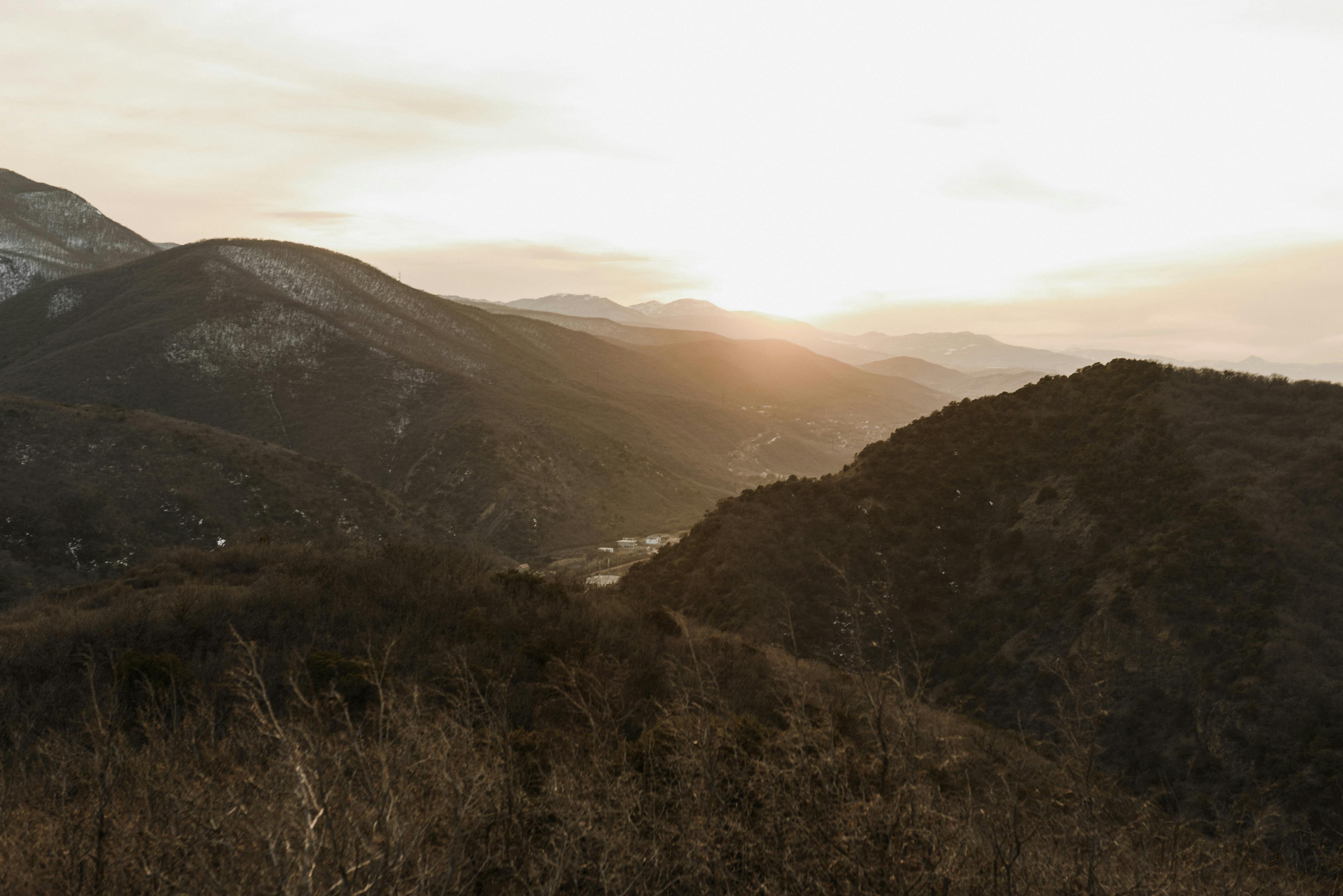 Peaceful mountain valley at sunset with soft light and natural scenery.