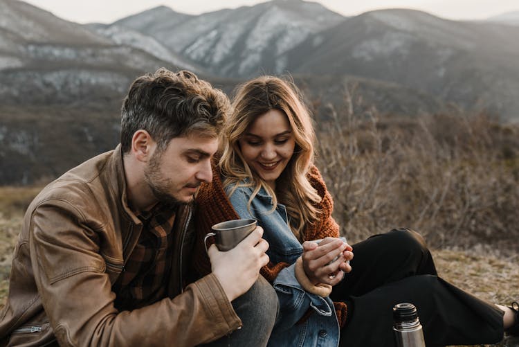 Man Holding A Cup Beside A Smiling Woman