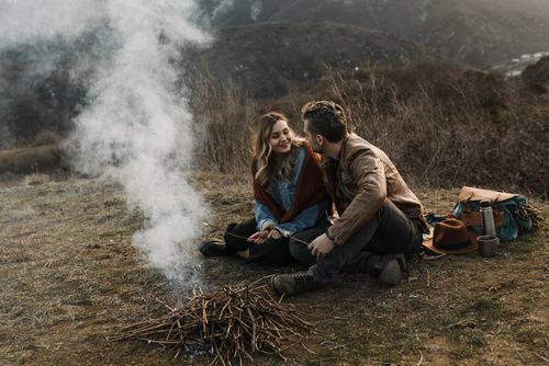 Free Couple enjoying a warm campfire in a serene outdoor setting, embracing nature. Stock Photo