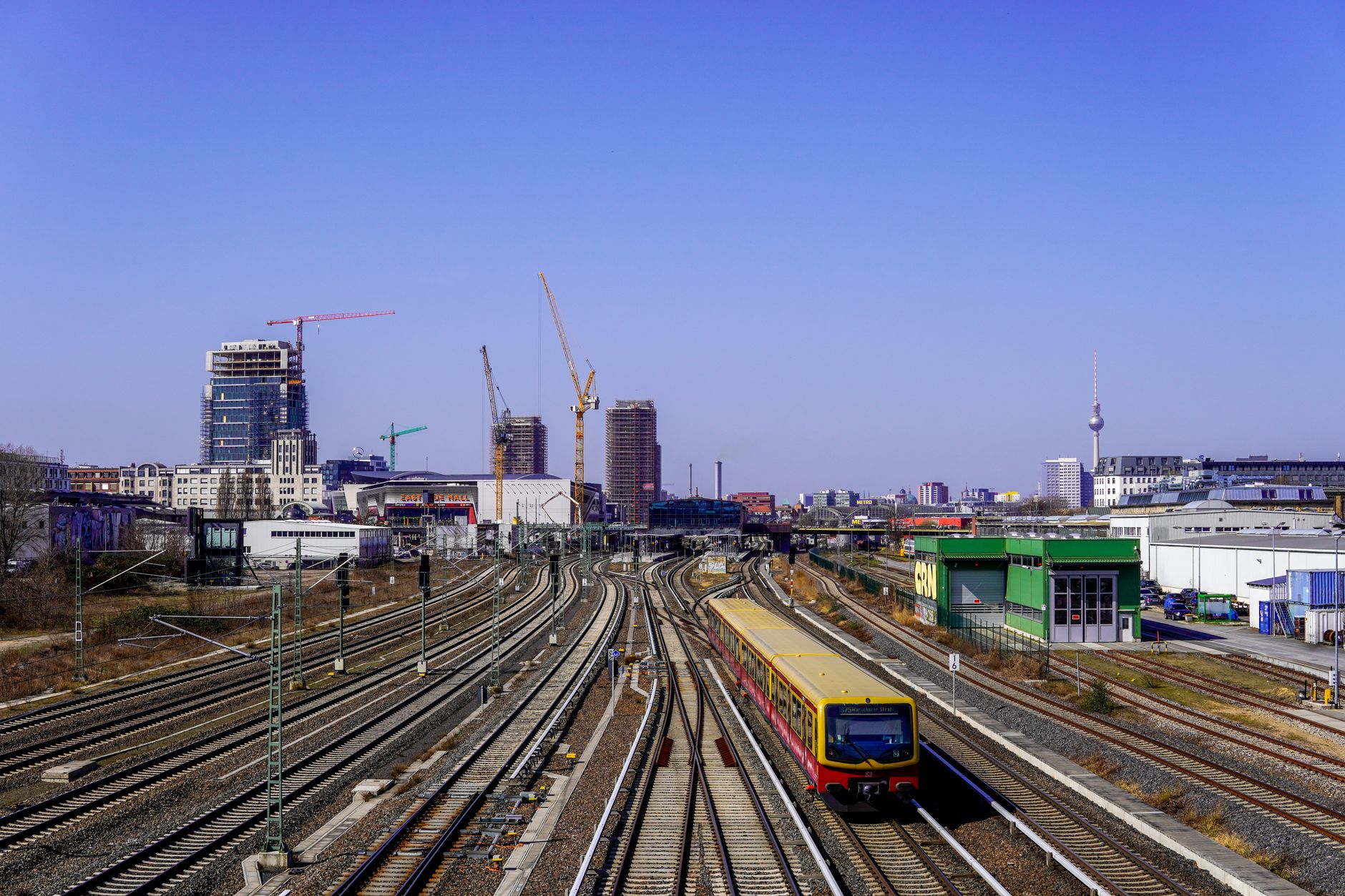 A vibrant Berlin train scene featuring the iconic TV Tower and busy railroads.