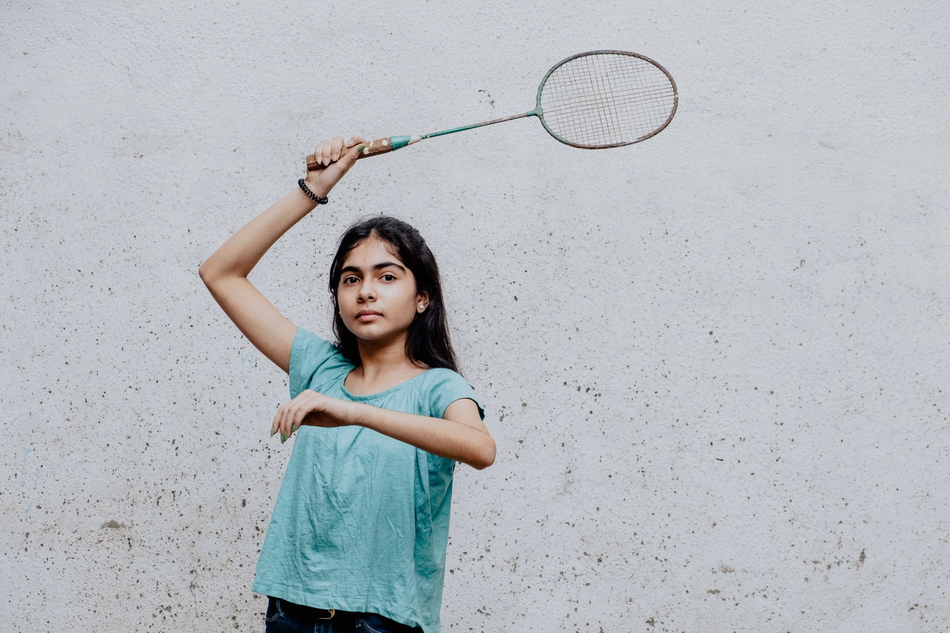 A young girl deeply focused as she plays badminton, showcasing skill and concentration.